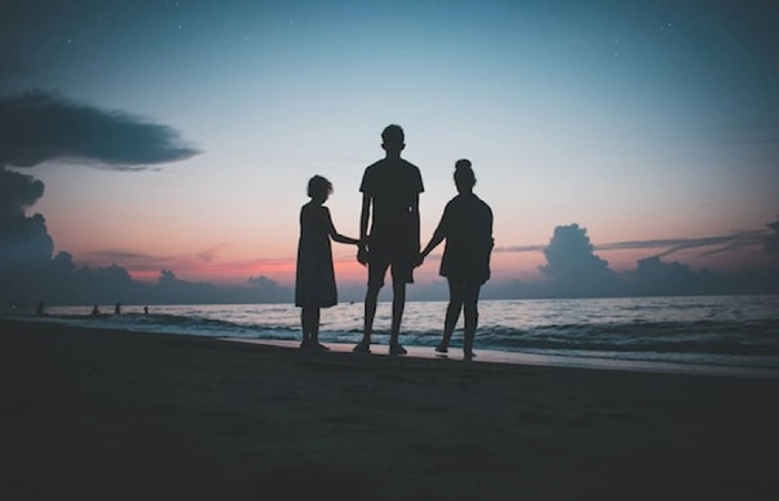 Family standing silently on a beach at sunset after conflict