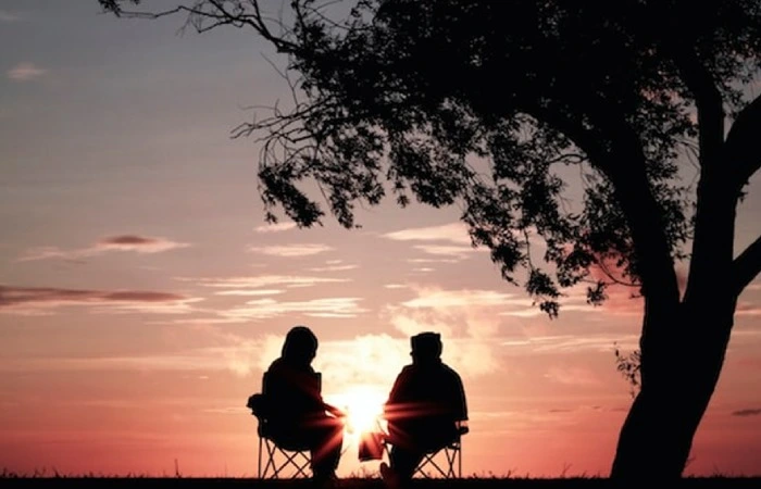 Two people sitting apart in silence at sunset